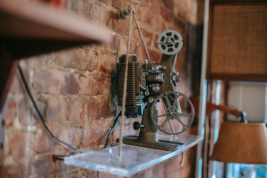 Destinos em Alta — Retro film projector placed on glass shelf near brick wall in cozy apartment