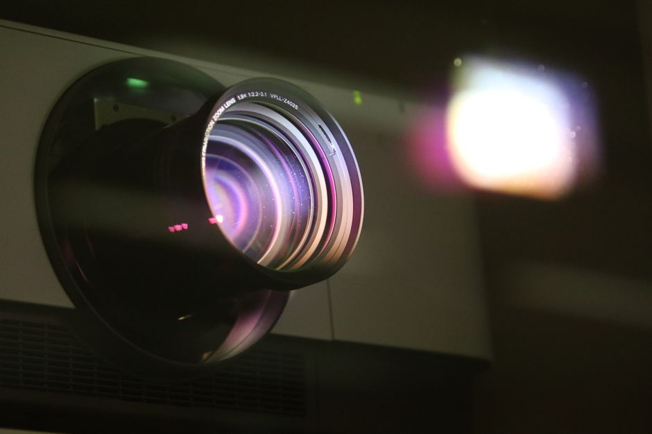 Destinos em Alta — Detailed view of a projector lens emitting light, showcasing optical technology.